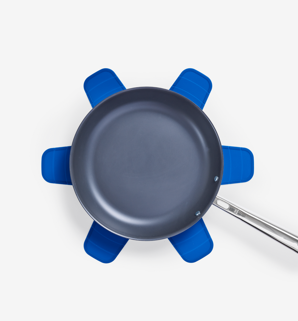 Nonstick frying pan resting on blue silicone pot holders trivet